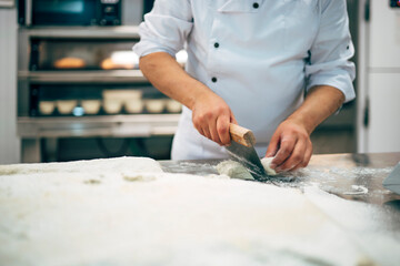 Baker working with dough in bakery