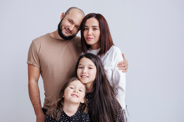 Parents and children embracing while standing against white background