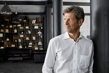 Mature man in loft leaning against a column