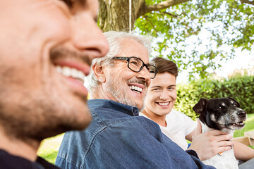 Men of a family sitting on a swing bed ing the garden, talking