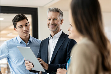Portrait of smiling mature businessman and employees in office