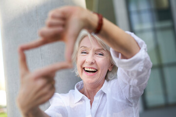 Portrait of laughing mature woman shaping frame with her fingers