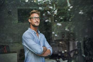 Casual young businessman behind windowpane in office