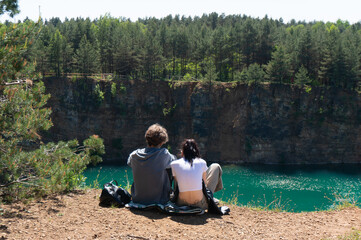 Young lovers sitting on bank of former quarry. Park Grodek. Jaworzno, Poland.