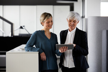 Two businesswomen sharing tablet in office