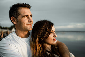 Smiling man looking away while embracing woman