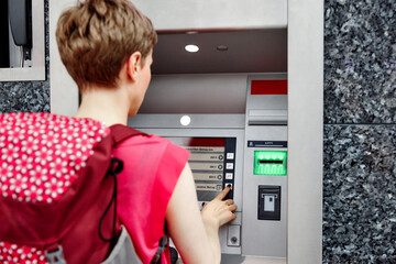 Rear view of woman using cash machine