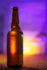 A bottle of cold beer in drops of water on a purple background