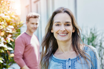 Portrait of smiling woman with man in background