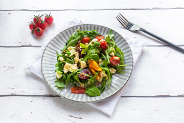 Plate of lowcarbvegetarian salad with arugula, tomatoes, nuts and Mozzarella cheese