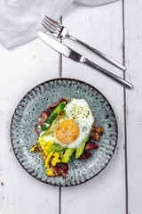 Fried egg with bacon, sliced avocado and Parmesan cheese