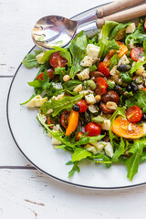 Plate of lowcarbvegetarian salad with arugula, tomatoes, nuts and Mozzarella cheese
