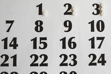 White pills on the calendar close-up, increasing dosage of medication by days, dosage escalation,...