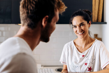 Portrait of young woman smiling at boyfriend in the kitchen