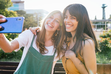 Portrait of two happy friends taking selfie with smartphone