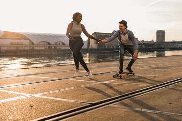 Young couple skateboarding at the riverside
