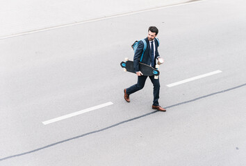Businessman with takeaway coffee and skateboard walking on the street © tunedin