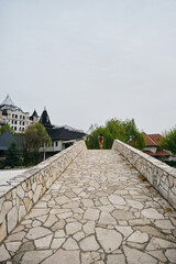 A young girl stands on a stone old bridge and enjoys the views of nature and buildings. Hotel...