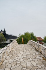 A young girl stands on a stone old bridge and enjoys the views of nature and buildings. Hotel...