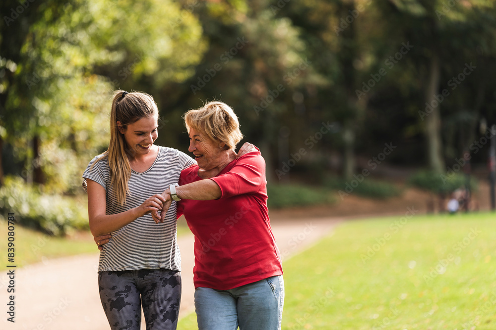 Wall mural Granddaughter and grandmother having fun, jogging together in the park