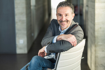 Portrait of a smiling mature businessman sitting on chair in office