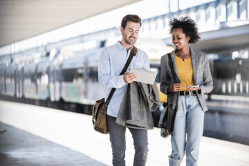 Young businessman and businesswoman using tablet together at the train station