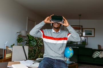 Businessman using virtual reality headset while sitting on desk at home