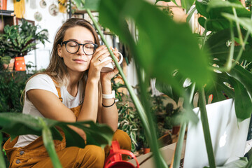 Young woman having a coffee break in a small gardening shop