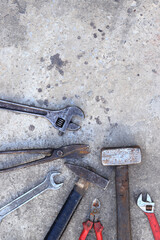 Old working tools on a concrete surface, top view. Hammers, sledgehammer, metal shears, adjustable wrench and wrench. Hand tool. Builder's Day or Father's Day. Construction and renovation concept