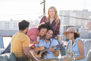 Friends having a rooftop party and playing guitar