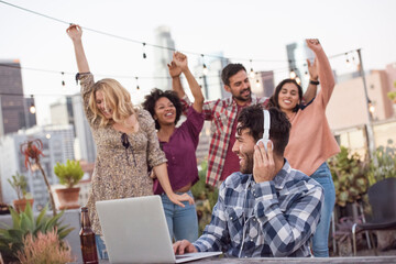 People dancing at rooftop party, with DJ using laptop