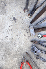 Old working tools on a concrete surface, top view. Hammers, flat file, tin snips, adjustable wrench...