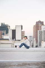 Young woman sitting on balustrade of a rooftop terrace