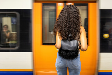 UK, London, rear view of young woman waiting at underground station platform