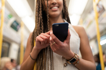 Happy woman looking at cell phone in underground train, London, UK