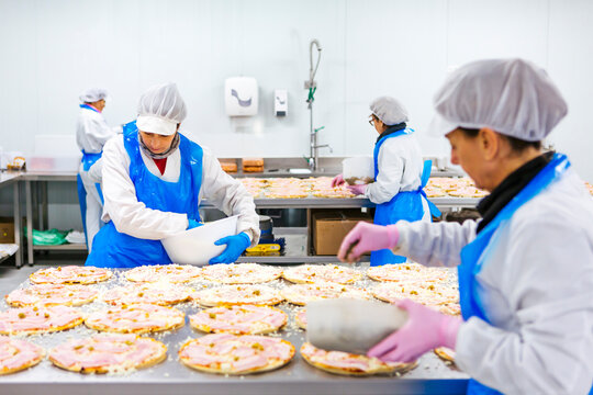 Women preparing pizzas in pizza company