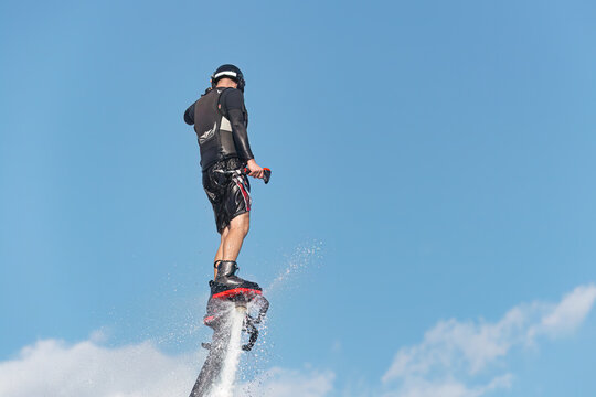 Man performing water jetpack flight against blue sky