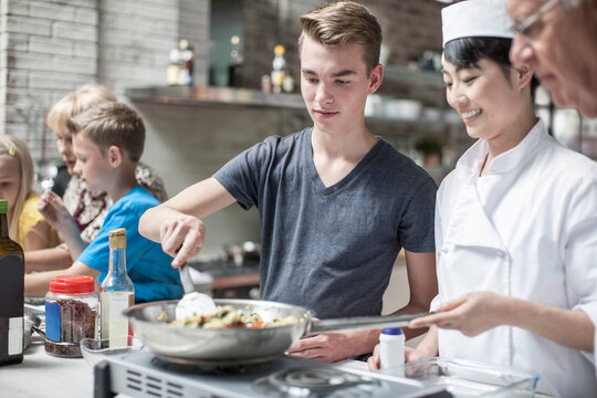 Teenager and female chef cooking together
