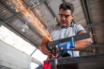 Mechanic using angle grinder in car workshop