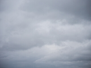 A cloudy sky with no sun. The sky is grey and the clouds are white. Nature background for design