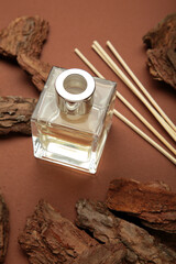 Home perfume reed diffuser with wood on brown background. Vertical photo.