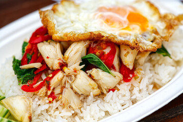 Close up delicious spicy menu of Thai food, stir fried holy basil with crab meat over rice with fried chicken egg.