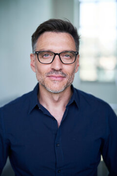 Portrait von einem mittel alten Mann mit Brille und Dreitagebart im Dunkelblauen Hemd