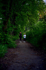 mother and daughter run together along a green alley