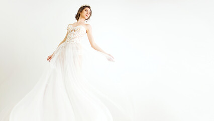 young smily brunette sexy girl in a white wedding boudoir dress and crown in hairstyle is dancing...