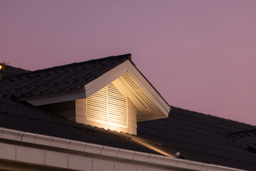 A roof with a light shining on it. garret roof shingle.