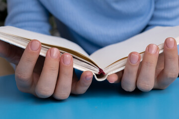 Pastel softness manicured nails with paper notebook on blue background. Woman showing her new manicure in colors of pastel palette. Simplicity decor fresh spring vibes earth-colored neutral tones