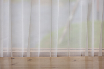 A window with white curtains and a wooden floor