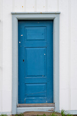 An old blue painted wooden door without doorknob and door lock on an old house