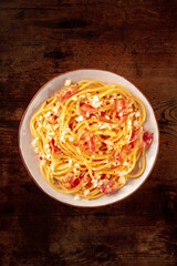 Carbonara pasta dish, traditional spaghetti with pancetta and cheese, shot from the top on a wooden background